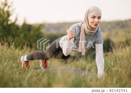 Portrait of attractive young Muslim woman smiling and doing plank. Portrait of attractive young Muslim woman smiling and doing plank. 92142541