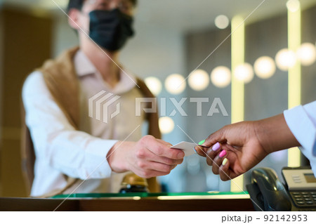 Hand of black woman taking keycard held by male guest over reception counter 92142953