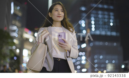 会社帰りにスマホを見るビジネスウーマン 女性 スマートフォン 会社帰りにスマホを見るビジネスウーマン 女性 スマートフォン 92143338