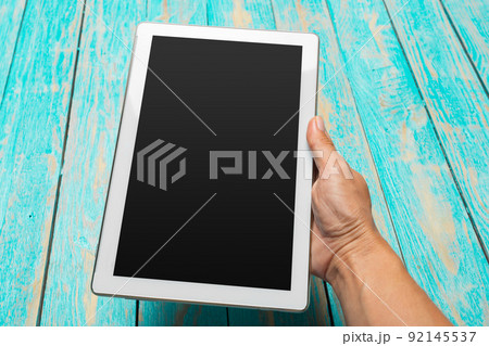 woman holding blank tablet device over a wooden workspace table woman holding blank tablet device over a wooden workspace table 92145537