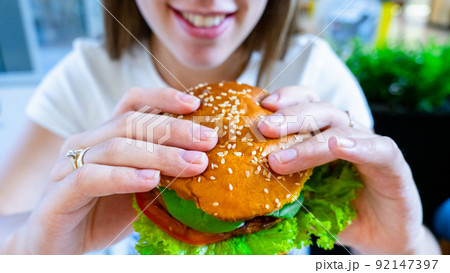 Vegan sandwich healthy vegetarian burger. Cute cheerful girl eating veggie hamburger with salad, avocado, vegetable. Vegetarian diet food concept. 92147397