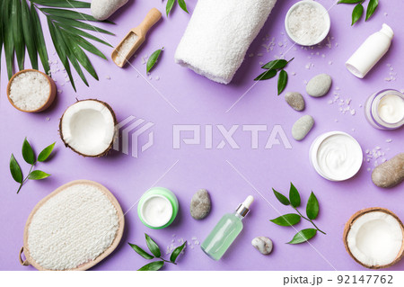 Coconut with jars of coconut oil and cosmetic cream on colored background. Top view. Free space for your text. Natural spa coconut cosmetics and organic treatment concept Coconut Spa composition 92147762