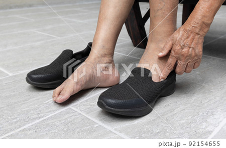 Elderly woman varicose veins feet puts on a shoes at home. 92154655