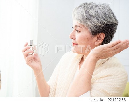 Portrait of mature aged asian woman 60s sprays perfume. Portrait of mature aged asian woman 60s sprays perfume. 92155288