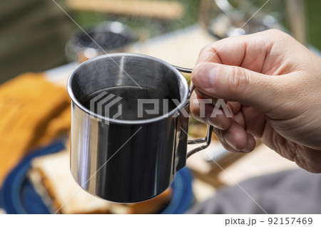 屋外キャンプでコーヒーを淹れて飲む男性の手元 屋外キャンプでコーヒーを淹れて飲む男性の手元 92157469