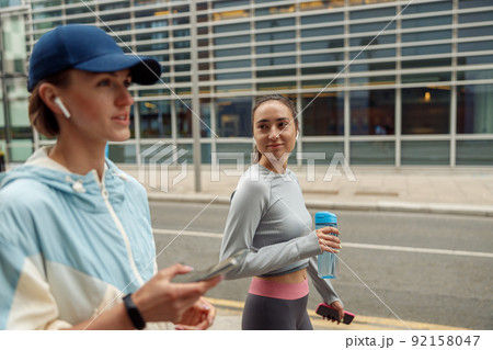 Two sportive young female friends walking city after morning running 92158047