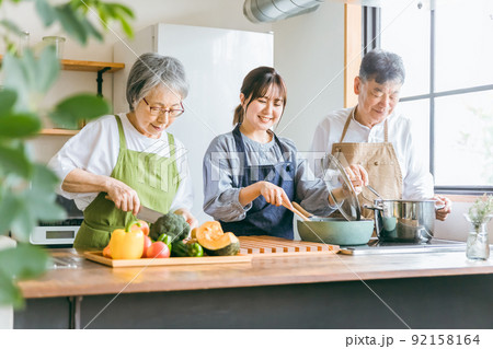 キッチンで料理する高齢者夫婦と若い日本人女性（料理教室） 92158164