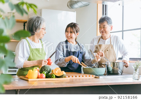 キッチンで料理する高齢者夫婦と若い日本人女性（家事代行・介護・） 92158166