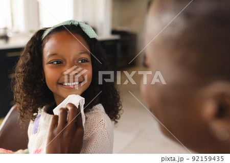 Image of happy african american girl eating breakfast with mother Image of happy african american girl eating breakfast with mother 92159435