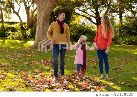 Image of happy caucasian parents and daughter in autumn garden Image of happy caucasian parents and daughter in autumn garden 92159620