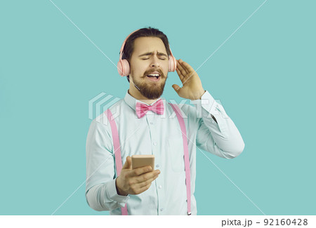 Young positive Caucasian man listens to music in headphones with eyes closed and sings along 92160428