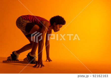 Image of african american female athlete preparing for run in neon orange lighting Image of african american female athlete preparing for run in neon orange lighting 92162163