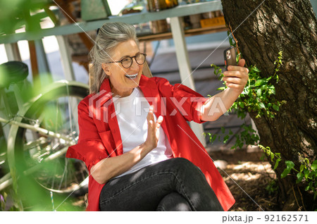 A woman in red shirt sitting outside and spending time online 92162571