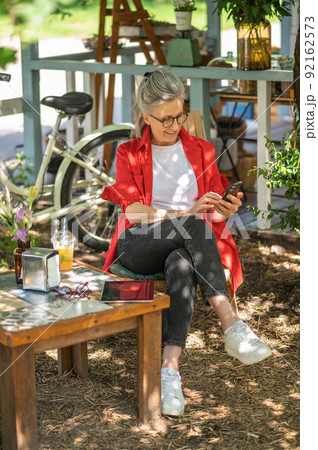 A woman in red shirt sitting outside and spending time online 92162573