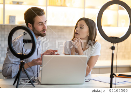 Two vloggers having online tutorial and looking involved Two vloggers having online tutorial and looking involved 92162596