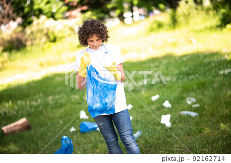 Curly-haired teen looking concentrated while gathering litter 92162714