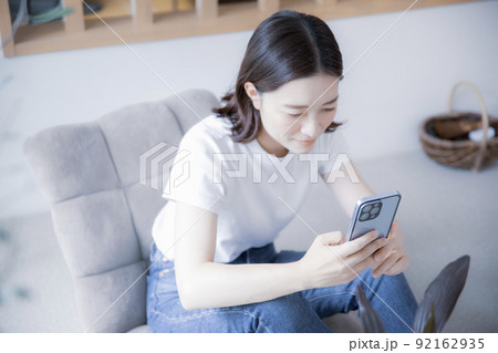 明るい室内でスマートフォンでインターネットを閲覧する日本人女性 92162935