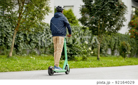 man in helmet riding electric scooter on street 92164029