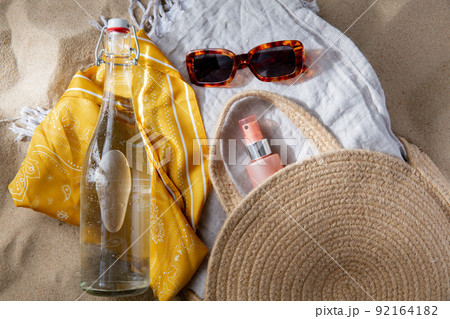 sunglasses, bag, water bottle, sunscreen on beach sunglasses, bag, water bottle, sunscreen on beach 92164182