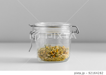 close up of jar with dried chamomile on table 92164282