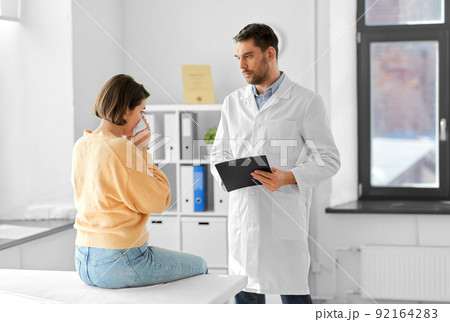male doctor and woman blowing nose at hospital male doctor and woman blowing nose at hospital 92164283
