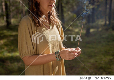 woman with smoking incense stick in forest woman with smoking incense stick in forest 92164295