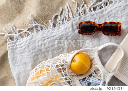 bag of oranges, sunglasses and magazine on beach 92164334