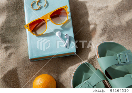 slippers, orange, earbuds and sunglasses on beach slippers, orange, earbuds and sunglasses on beach 92164530