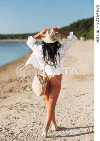 woman with bag walking along summer beach 92164695