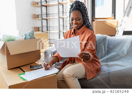 woman with bills and calculator moving to new home 92165249