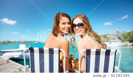 beautiful happy women sunbathing on beach chairs 92165395