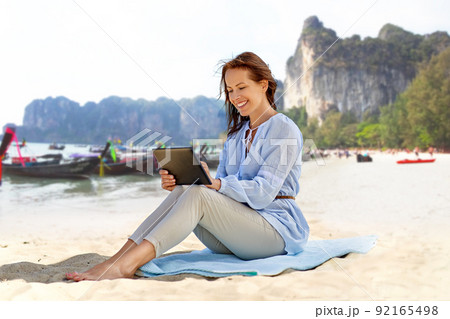 happy smiling woman with tablet pc on summer beach 92165498