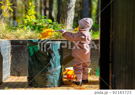 happy little baby girl helping clean up backyard 92165725