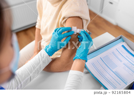 nurse applying medical patch to vaccinated woman nurse applying medical patch to vaccinated woman 92165804