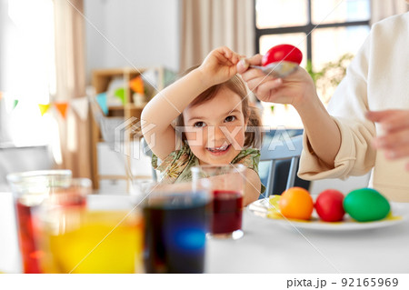 mother with child dyeing easter eggs at home 92165969