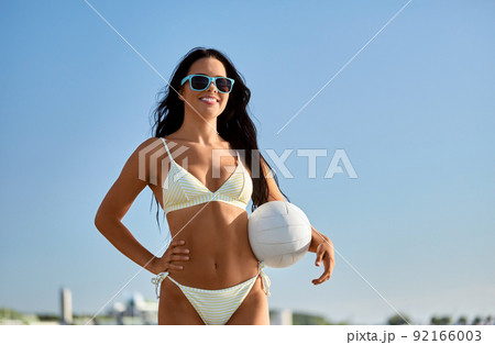 woman in bikini posing with volleyball on beach 92166003