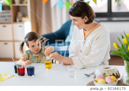mother with child dyeing easter eggs at home 92166170