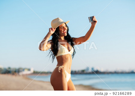smiling woman in bikini taking selfie on beach smiling woman in bikini taking selfie on beach 92166289