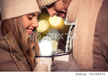 happy couple with tea cups over christmas lights happy couple with tea cups over christmas lights 92166291