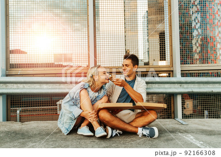 happy couple eating pizza on city roof top parking 92166308