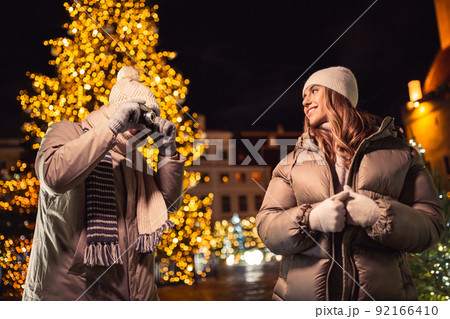 couple with camera photographing at christmas city couple with camera photographing at christmas city 92166410