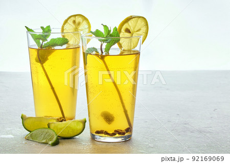 Two glass cups of homemade fermented kombucha tea are decorated with mint and lemon on a light gray concrete table 92169069