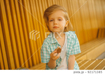 Portrait of cute boy looking at camera with a chocolate bar Portrait of cute boy looking at camera with a chocolate bar 92171385
