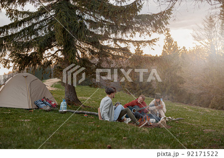 Caucasian team of friends hikers resting with guitar playing at tent in mountains. . 92171522