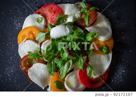 Homemade caprese salad with mozzarella, tomatoes and basil on slate. Top view. Homemade caprese salad with mozzarella, tomatoes and basil on slate. Top view. 92172107