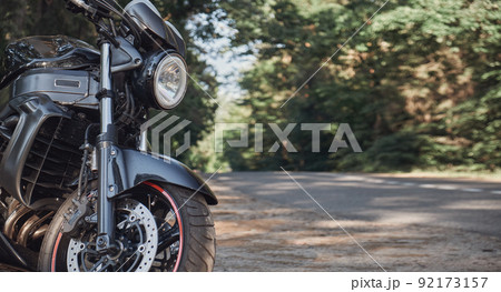 Black road bike in the forest on the roadside of the asphalt road, no people Black road bike in the forest on the roadside of the asphalt road, no people 92173157