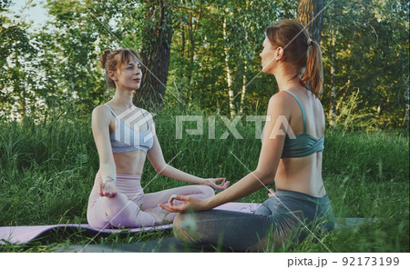Two young women doing yoga outdoors, mental health care Two young women doing yoga outdoors, mental health care 92173199