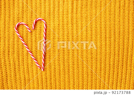 Candy cane heart for christmas design on orange knitted background with copy space . X-mas or valentines day concept 92173788