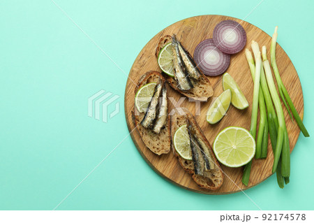 Board with sandwiches with sprats on mint background Board with sandwiches with sprats on mint background 92174578