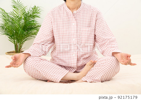パジャマを着て寝室で瞑想をするミドル女性 92175179